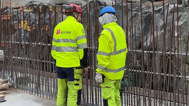Byggnadsarbetare samtalar vid betongbygge