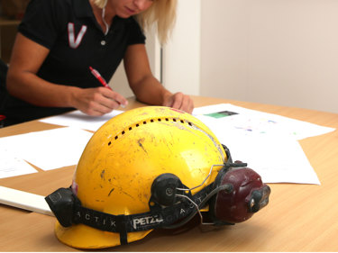 Person som skriver på papper med en bygghjälm i förgrunden